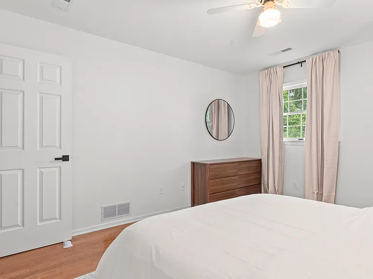 Comfortable upper-level bedroom with a queen bed, dresser, ceiling fan, and closet storage.