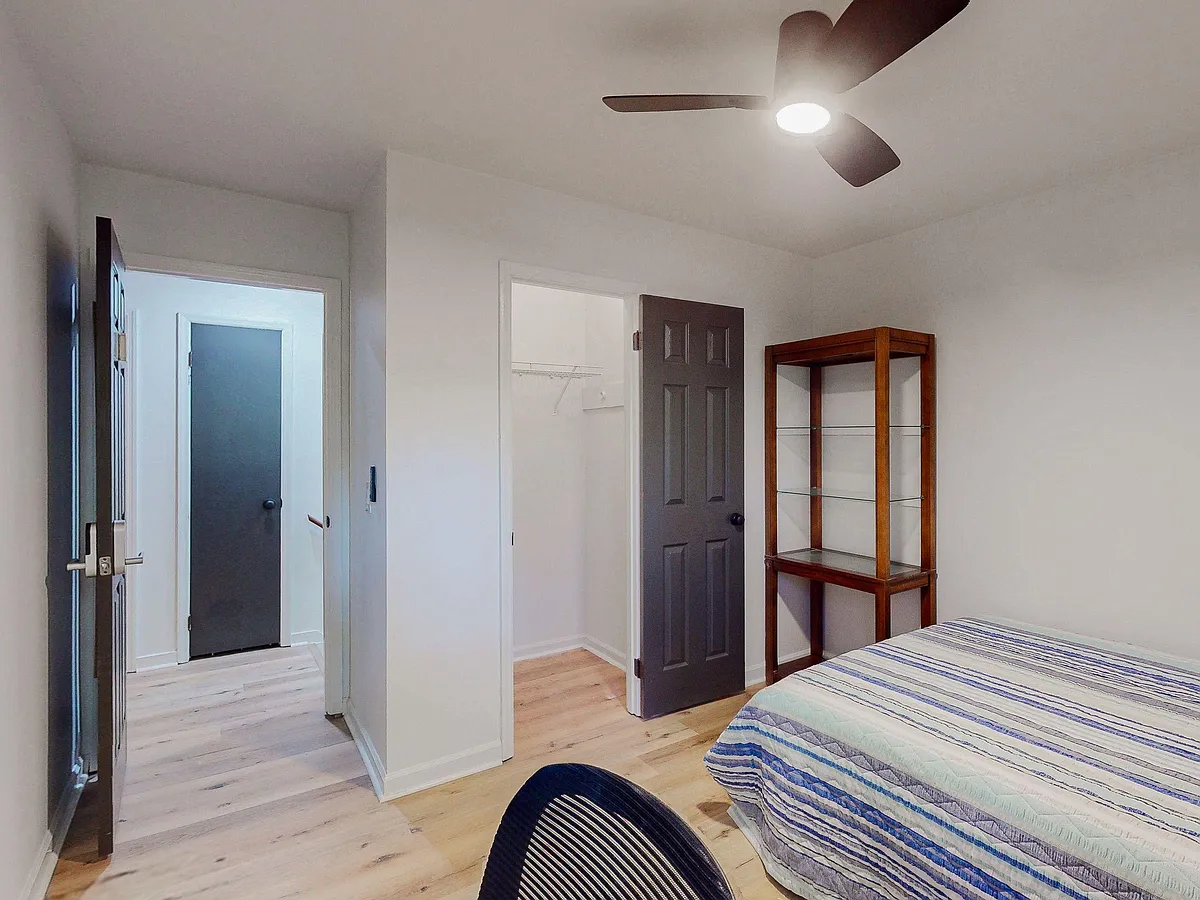 Private bedroom with ceiling fan, light-toned flooring, and convenient closet storage; furnished with a bed and shelving. - Satellite Blvd