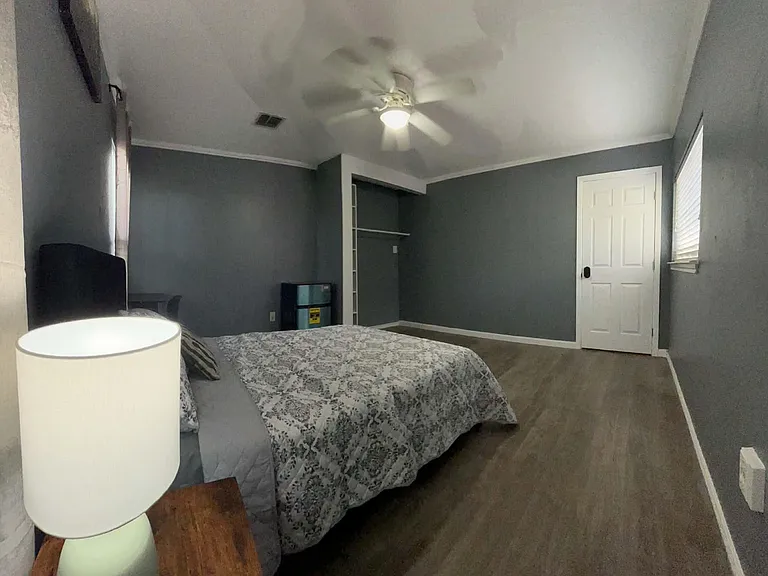 Bedroom with ceiling fan, hardwood-style floors, and an open closet system, plus windows for natural light.