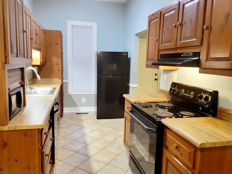 Galley Kitchen with Hickory cabinets, ceramic tile floor, stove, dishwasher, microwave, garbage disposal, and refrigerator with ice maker