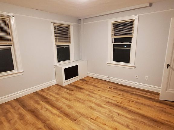 Front room / Living room. The door on the right is the closet. The box in the center is a radiator cover.