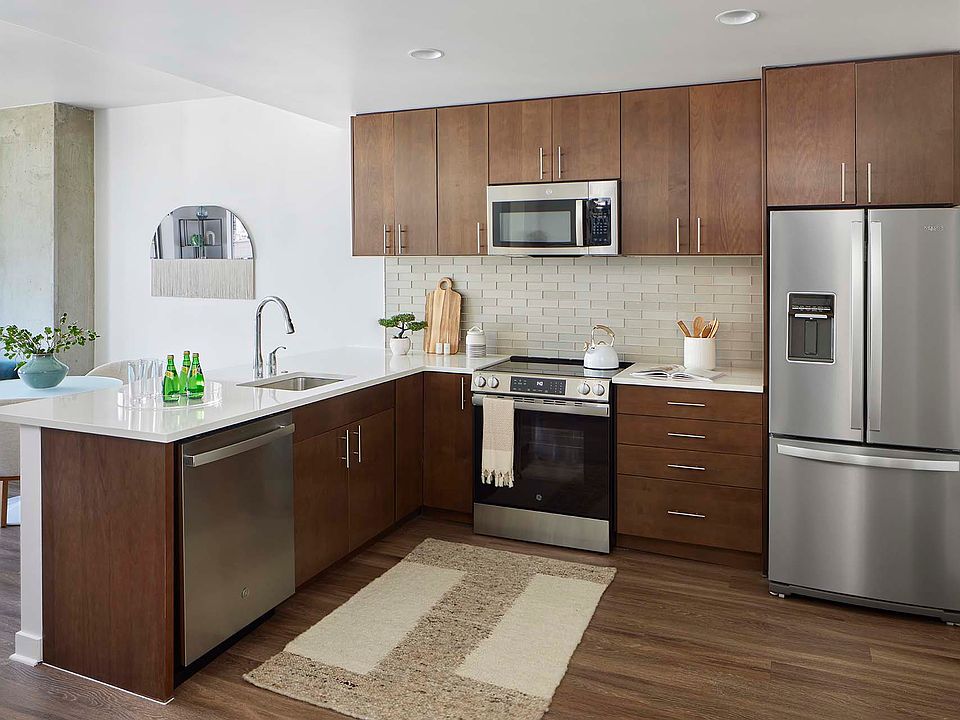 Apartment kitchen with wood style flooring and stainless steel appliances.