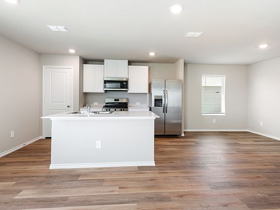 Kitchen featuring appliances with stainless steel finishes, recessed lighting, white cabinetry, an island with sink, and light wood-style flooring