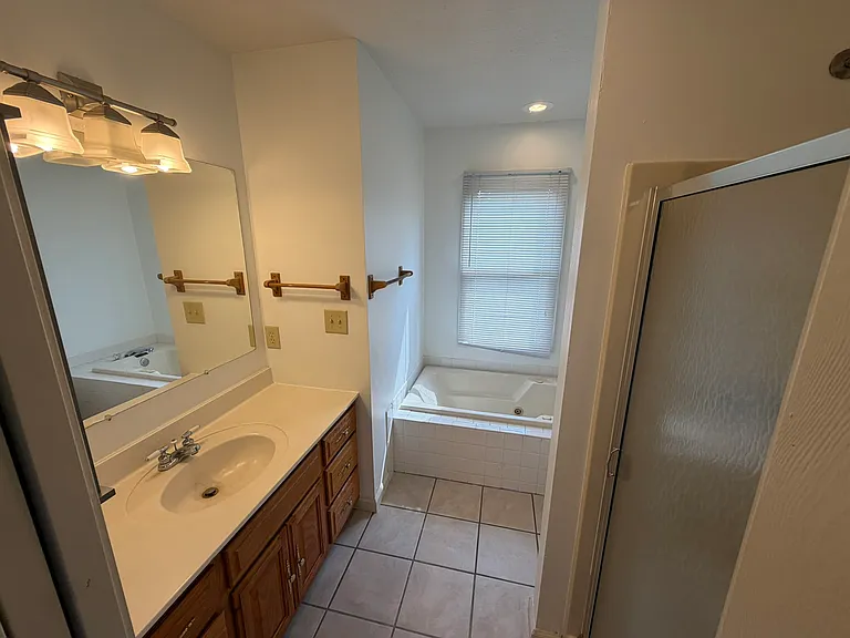 Master bath with jetted tub, shower, just polished oak cabinets and ceramic tile,