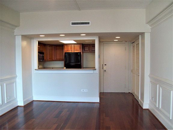 living area facing the kitchen and entrance door. To the right of the entrance door is a large utility closet.