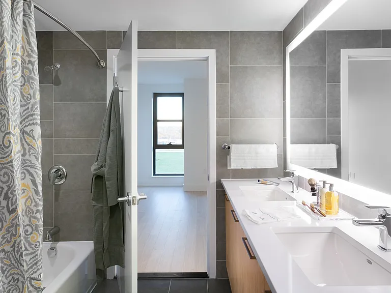 Luxurious double-sink bathrooms with sleek tile surround and backlit mirros