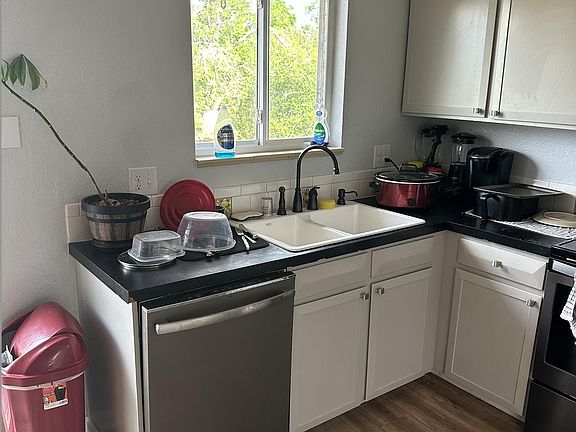 Compact kitchen with ample cabinetry, double-basin sink, dishwasher, and a window over the counter for ventilation.
