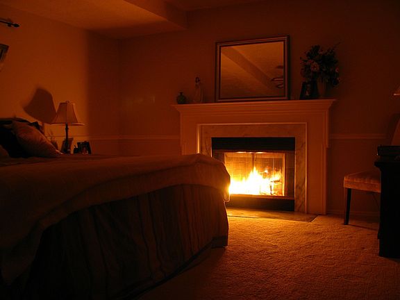 Master Bedroom illuminated by a bedside fire.