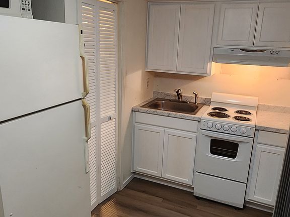 Kitchen with new cabinets, sink, faucet, and flooring.
