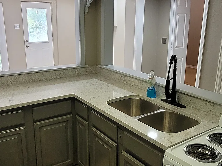 Another picture of kitchen taken from kitchen doorway located in the back room (Rm #2), looking at front door in front room (Rm #1), and door to bedroom (Rm #3) can be seen right behind the faucet and to the left of the pantry door.