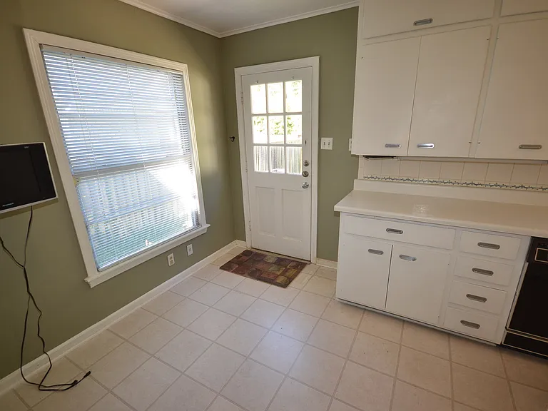 Kitchen space featuring white cabinetry with silver-tone hardware, a white countertop, and a white tile backsplash