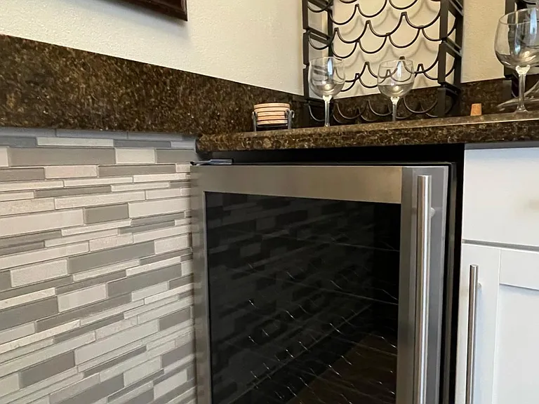 Wine closet has 2 wine fridges and wine racks over granite counter tops.