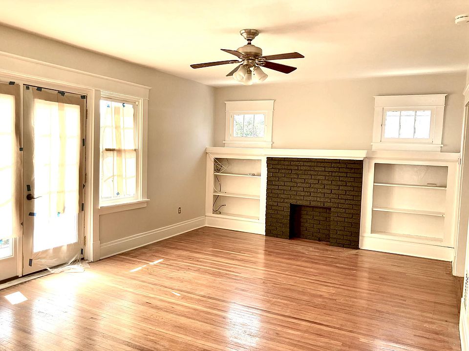 Living room, featuring decorative fireplace, built-in shelves, door to front porch, ceiling fan.