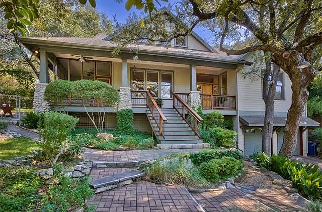 Street view of front of home with large front porch and screened porch and terraced gardens.