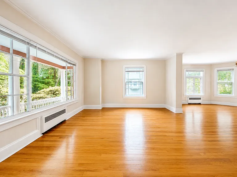 Light and bright living room with large picturesque window to front porch and Forest Park trail.