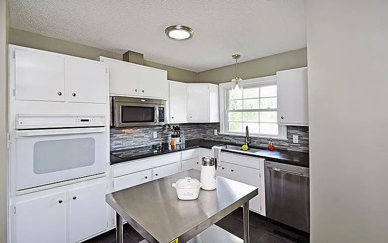 Kitchen with ceramic floor, granite counters and stainless appliances.