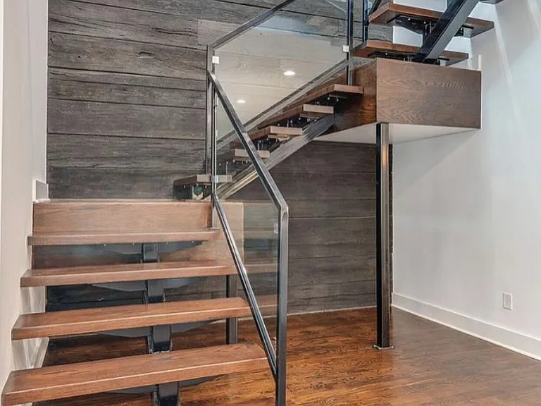 The wooden staircase to the 2nd floor has metal and glass railings. 1st floor to 2nd floor wood cladding on stair case wall.