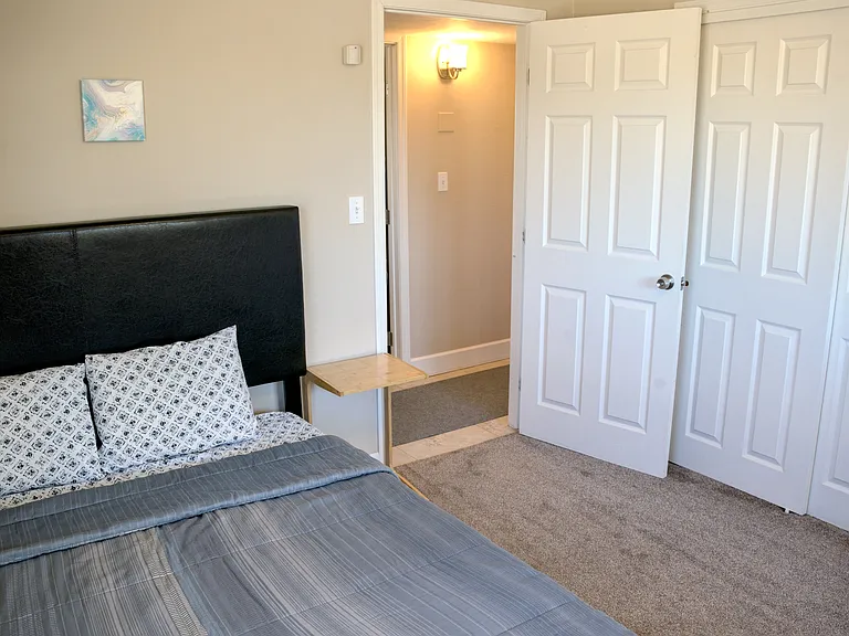 Bedroom 2 with queen bed, dresser, hangers, hanging closet organizer shelves, laundry basket, ceiling fan