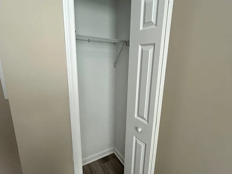 Reach-in closet with a built-in wire shelf and hanging space, ideal for everyday clothing and extra storage.