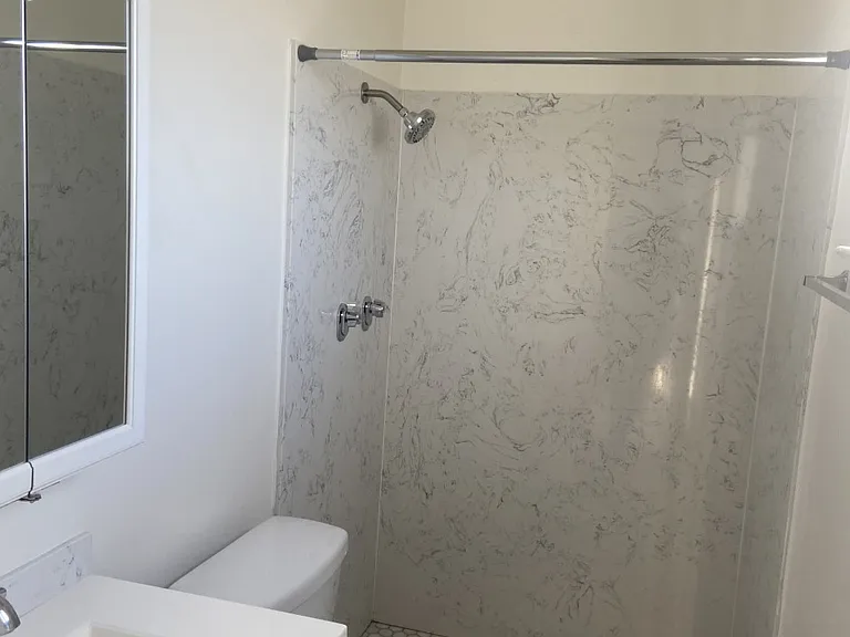 Beautiful sink enclosure with soft-touch pop-up features and a three-mirror medicine cabinet for added convenience. A screened window allows for fresh airflow, complemented by an antique-style light fixture.