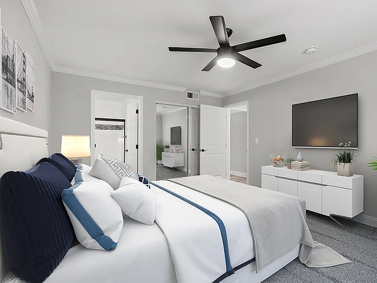 Carpeted bedroom with ceiling fan and private bathroom.