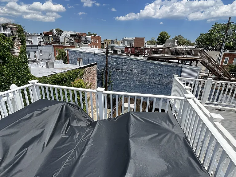 Outdoor roof deck with covered furniture (couch, chairs, and table), with view of the city