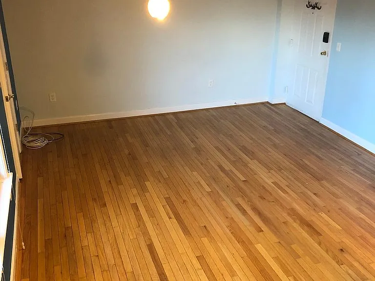 Living room. Looking south from edge of kitchen. Front door to right, windows and bedroom to left.