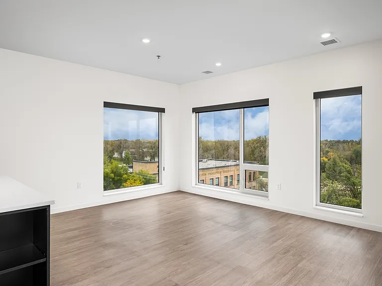 Spacious living room with large windows offering stunning views of lush greenery, featuring elegant wooden flooring and modern design. Spacious living room with large windows offering stunning views of lush greenery, featuring elegant wooden flooring and