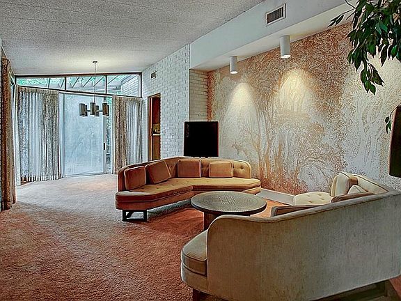 Original mid-century design featuring exposed brick, angled windows with embroidered wall in the formal living and dining. Glass door leads to deck offering a tranquil view.