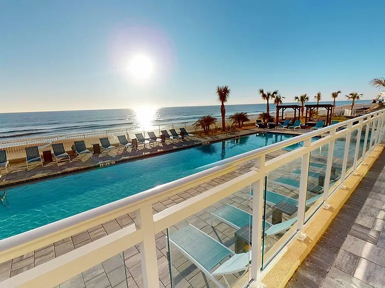 Luxurious beachfront pool with lounge chairs, overlooking the ocean at sunrise