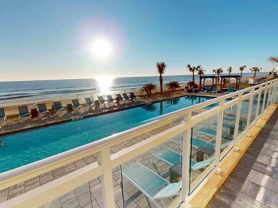 Luxurious beachfront pool with lounge chairs, overlooking the ocean at sunrise