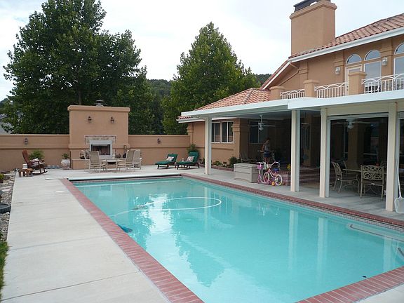 Poolside view of covered patio, hot tub, and fireplace