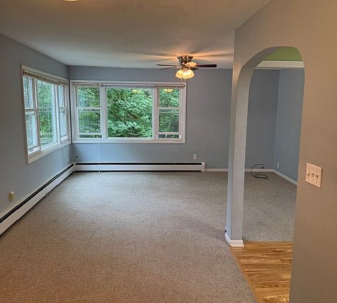 Open plan living areas. 
Dining room in foreground.
Big living room with sunny windows in behind.
