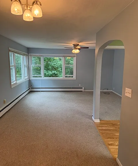 Open plan living areas. 
Dining room in foreground.
Big living room with sunny windows in behind.