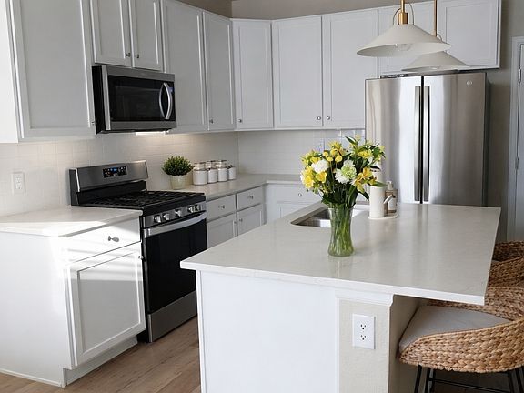 Modern farmhouse kitchen with stainless steel appliances and upgraded white quartz counter tops.