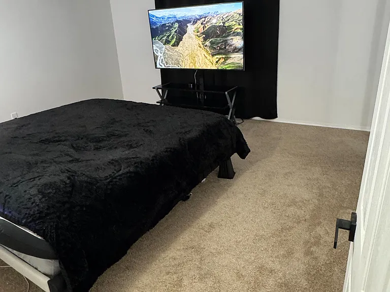 Carpeted bedroom featuring a comfortable King-sized bed and a clean, neutral wall design for a restful and simple layout.