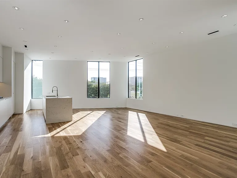 Expansive open-concept space featuring wood-finish flooring, recessed lighting, and large vertical windows
