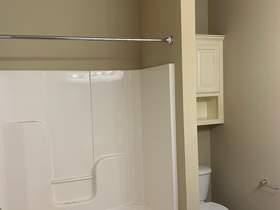 Large tub with shower and storage above toilet