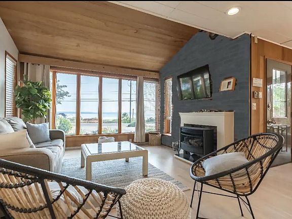 Living room with fireplace and floor to ceiling windows looking out to the ocean