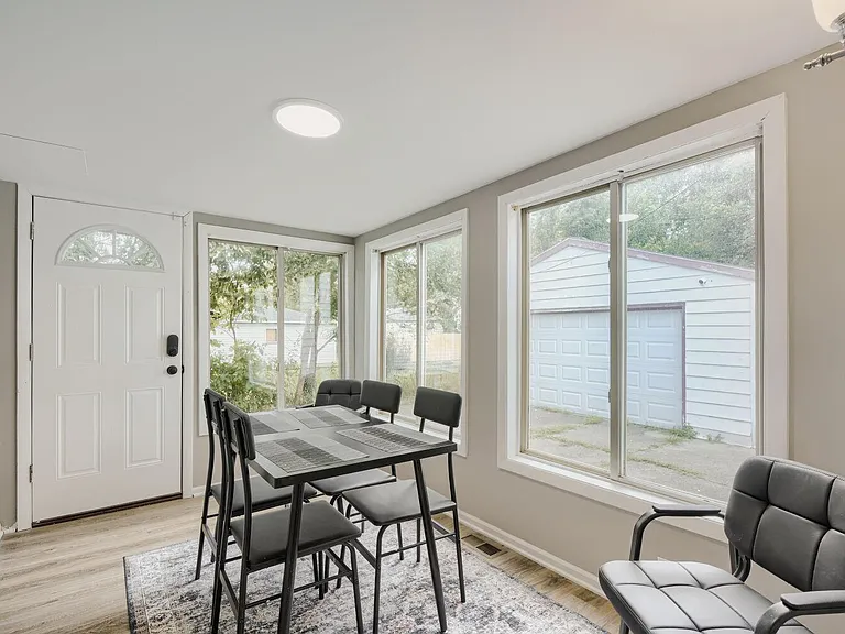 Dining area near the entry with a table setup and large windows offering yard views and plenty of natural light.