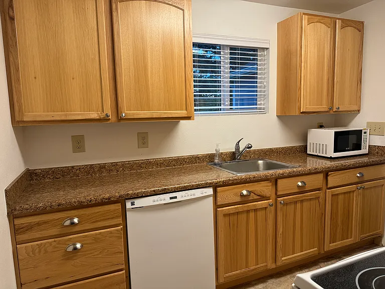 Nice cabinets with modern pulls in kitchen with dishwasher, oven/stove, microwave, and refrigerator.