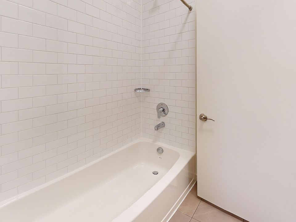 Clean, modern bathroom featuring a tiled shower area, a bathtub, and a door on the right.