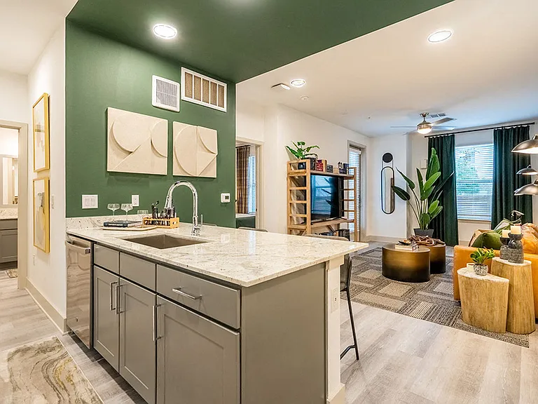 A modern kitchen with a green wall and a marble countertop.