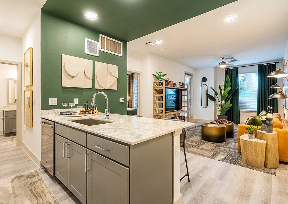 A modern kitchen with a green wall and a marble countertop.