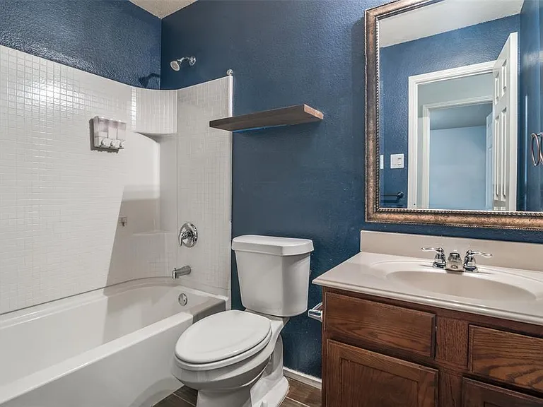 Full bathroom with toilet, tiled shower / bath combo, and vanity