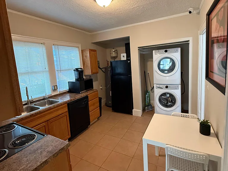 Functional kitchen with ample counter space, double-basin sink, full-size range and fridge, plus in-unit stacked laundry.