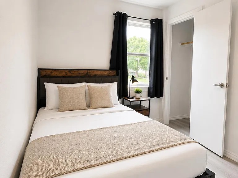 Private bedroom with a full bed, ceiling fan, and window with curtains, plus a nightstand and open closet storage.