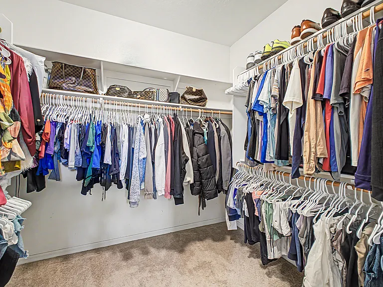 The spacious walk-in closet offers ample storage for clothing, shoes, accessories, and more.