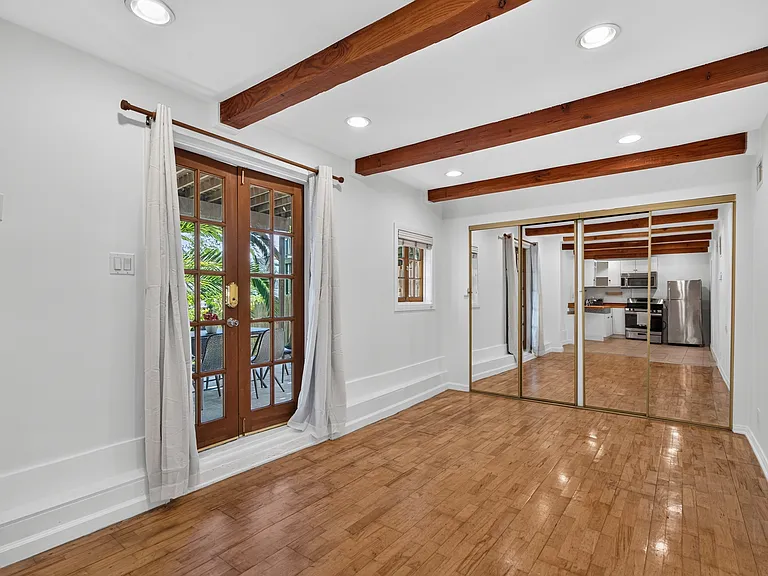 Inside studio (bed + living area) - wood beams, wood floors + french doors