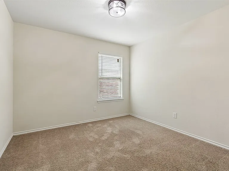 Carpeted room featuring neutral wall tones, a single window with horizontal blinds, and a flush-mount ceiling light fixture